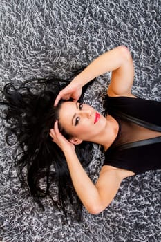 View of a beautiful young woman posing on top of a cool carpet.