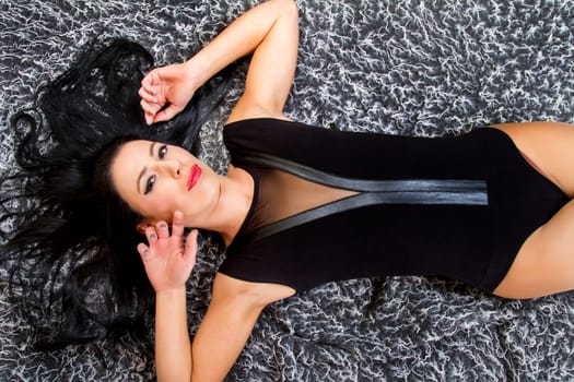 View of a beautiful young woman posing on top of a cool carpet.
