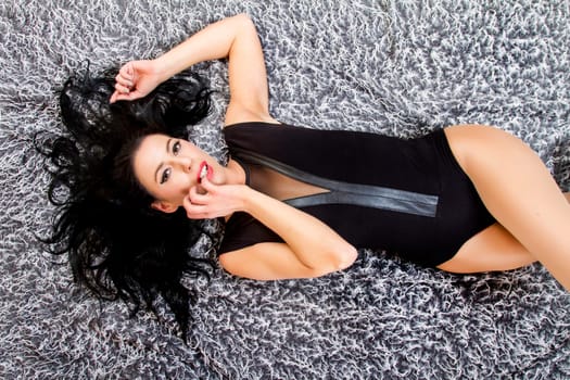 View of a beautiful young woman posing on top of a cool carpet.