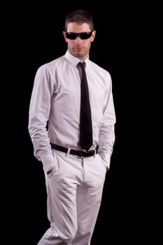 View of a handsome young man on a white suit with tie isolated on a black background.