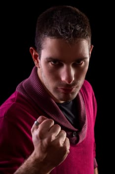 Face view of a young urban man with a mean look isolated on a black background.