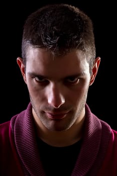 Face view of a young urban man with a mean look isolated on a black background.