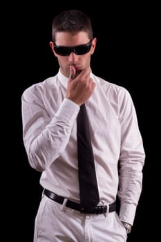 View of a handsome young man on a white suit with tie isolated on a black background.
