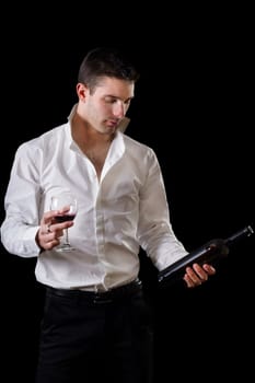 View of a young man holding a red glass of fine wine isolated on black studio background.
