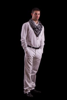 View of a young urban styled fashioned man standing isolated on a black background.