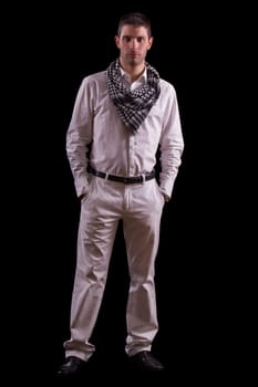 View of a young urban styled fashioned man standing isolated on a black background.