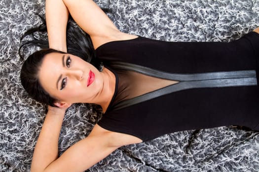 View of a beautiful young woman posing on top of a cool carpet.