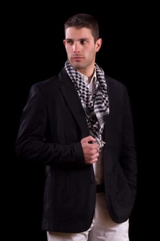 View of a young urban styled fashioned man standing isolated on a black background.