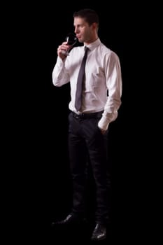 View of a young man holding a red glass of fine wine isolated on black studio background.