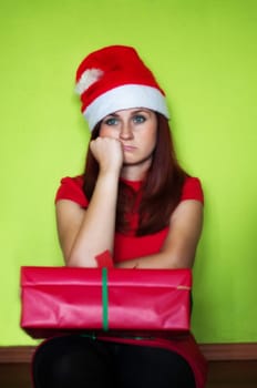 bored and disappointed woman holding a present on green wall