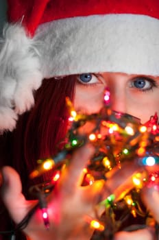woman with christmas garland lights close up on eyes