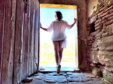 A 50-year-old blonde woman stands in a doorway, capturing the beauty of her travel adventure while exploring historical sites.