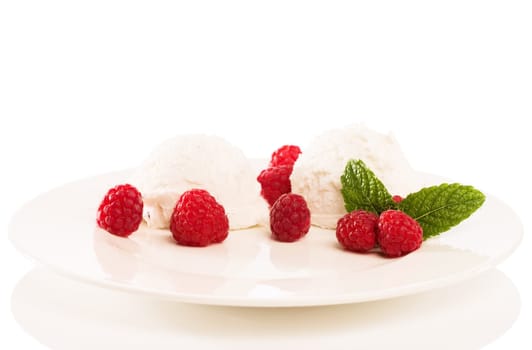Vanilla ice cream with raspberries on a plate against a white background