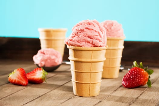 Strawberry ice cream on wood with strawberries and blue background