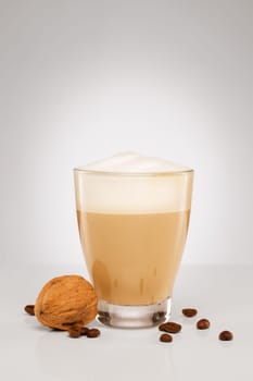 Cappuccino with coffee beans and walnut on grey background