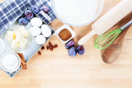 Baking ingredients for plum cakes from above on a wooden surface