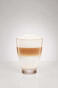 Latte macchiato in a small glass on a grey background