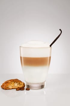 Latte macchiato with vanilla and cantuccini biscuit on grey background