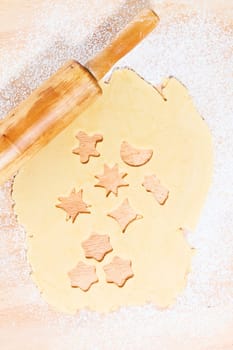 Cookies cut out of dough for Christmas with rolling pin from above