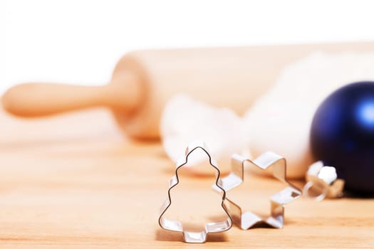 Close-up cookie cutter in Christmas tree shape for Christmas in front of Christmas bauble and baking ingredients