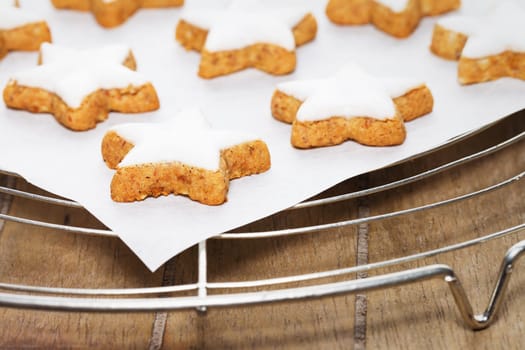 Cinnamon stars on baking paper on cake rack on wood