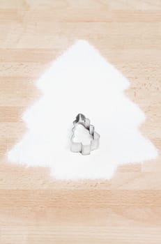 Christmas tree made of flour with cookie cutter in Christmas tree shape on wooden ground