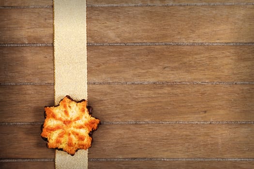 Coconut Christmas cookies on golden ribbon on wooden background