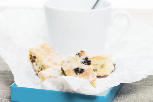 Small pieces of Christmas stollen on baking paper in front of a white cup