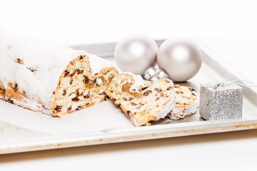 Marzipan stollen on baking tray with Christmas tree baubles and silver gift for Christmas