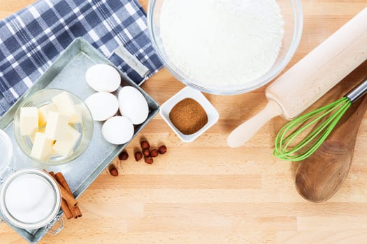 Baking utensils and baking ingredients from above on wooden background