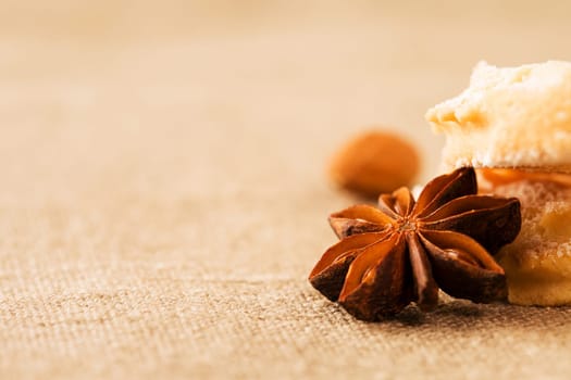 Close-up of star anise on fabric next to Christmas biscuits