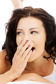 Face closeup of a beautiful young and fit woman yawning  while lying in bed.