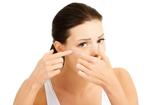 Young woman with pimple on her face. Trying to squeeze it. Isolated on white background.