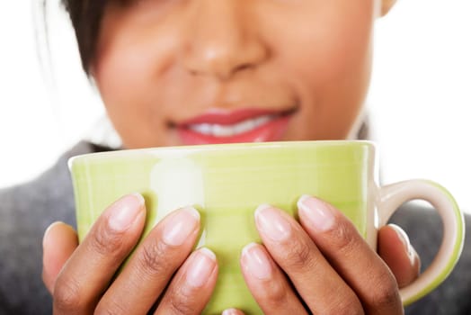Young woman drinking something from big mug, isolated on white