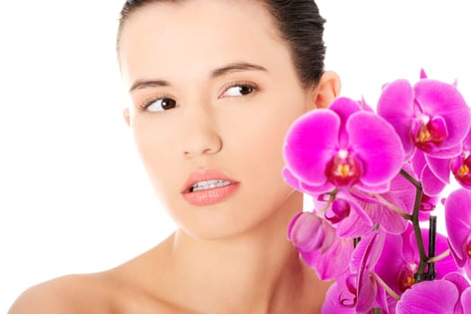 Portrait of beautiful young woman with health skin and with orchid flower. Spa concept.