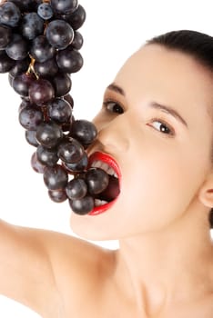 Beautiful sensual brunette eating grapes, isolated on white background