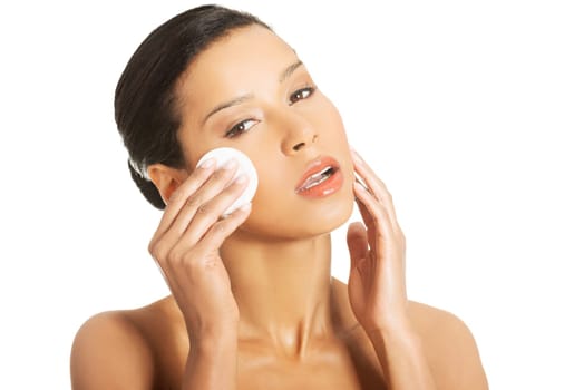 Portrait of happy young woman cleaning skin by cotton pad, over white background