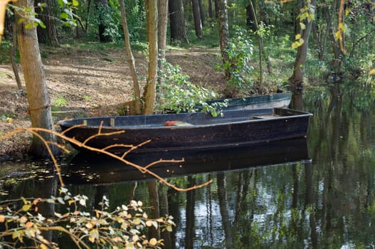 empty fishing barge on the shore of a forest lake  empty fishing boat on the edge of the forest lake