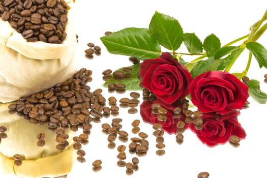 A bag of coffee beans and two red rose on a mirror