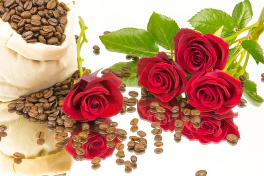 A bag of coffee beans and red roses on a mirror