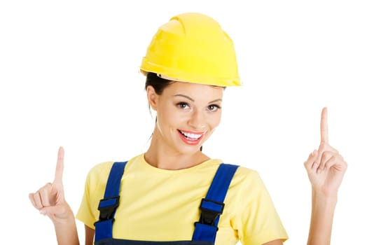 Female construction worker pointing on copy space, isolated on white