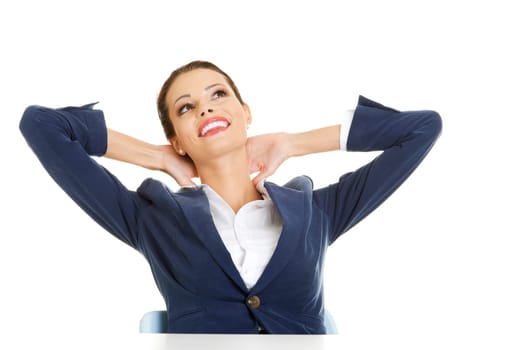 Young female executive relaxing with hands behind head