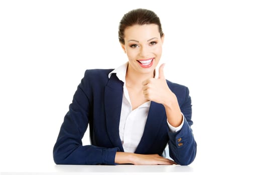 Young woman at the desk gesturing OK , isolated on white