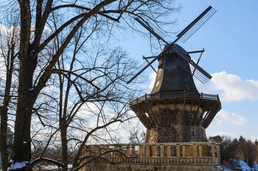 Winter landscape with traditional old windmill against blue sky background