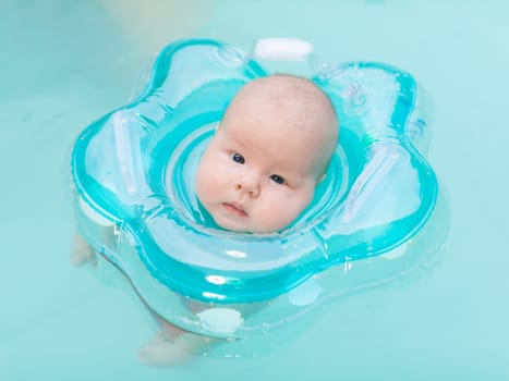 Baby swimming with neck swim ring in pool