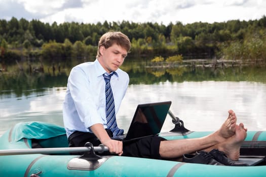 Dressed man in boat and reading from laptop