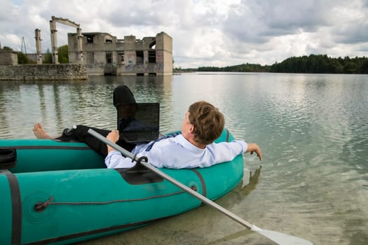 Dressed man lay over boat on lake shore