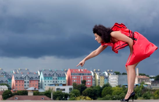 Woman in nice dress pointing on background house