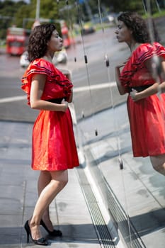 Woman in red dress adjust herself before mirror
