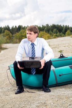 Dressed man sit on boat edge with laptop